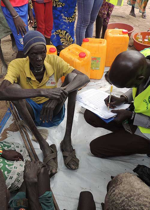 Man sitting on ground speaking with NGO worker