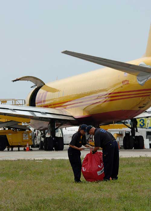 Staff packing a shipment in front of an airplane getting ready